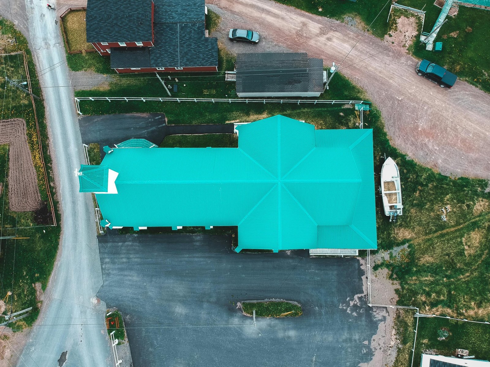 Aerial view of old church with blue roof and bell tower located near residential houses in countryside